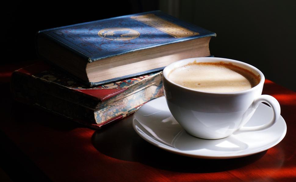 Old books and a cup of coffee on a wooden table